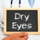 doctor holding chalk board with text "dry eyes" written on it