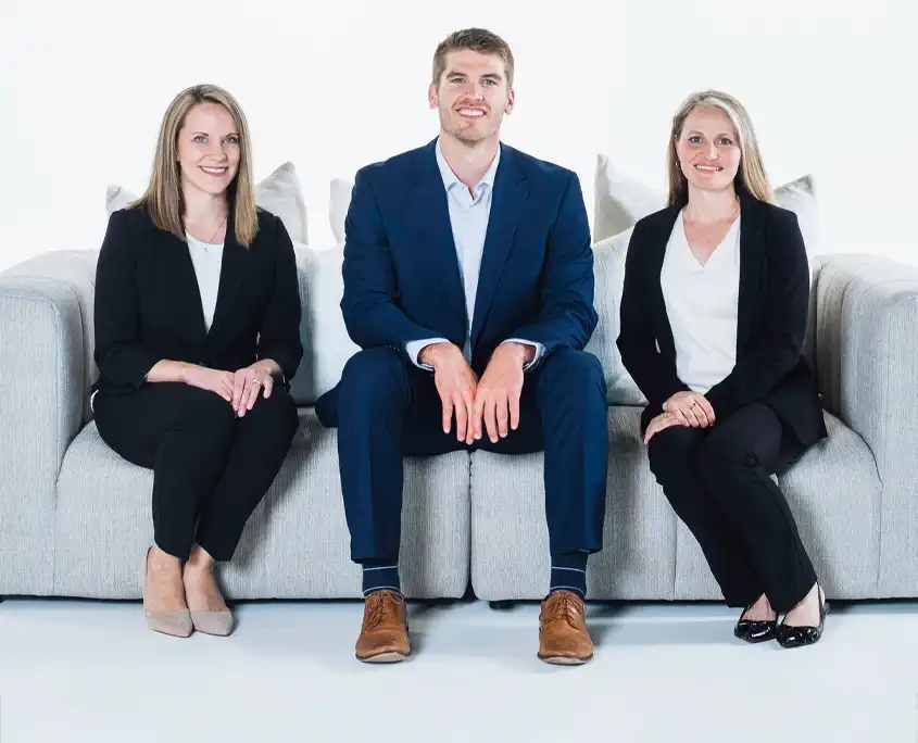 3 waterloo eye doctors sitting on a couch. pictured left to right, dr carrie menet, OD, dr brad boyle, OD, and dr carrie kearns, od.