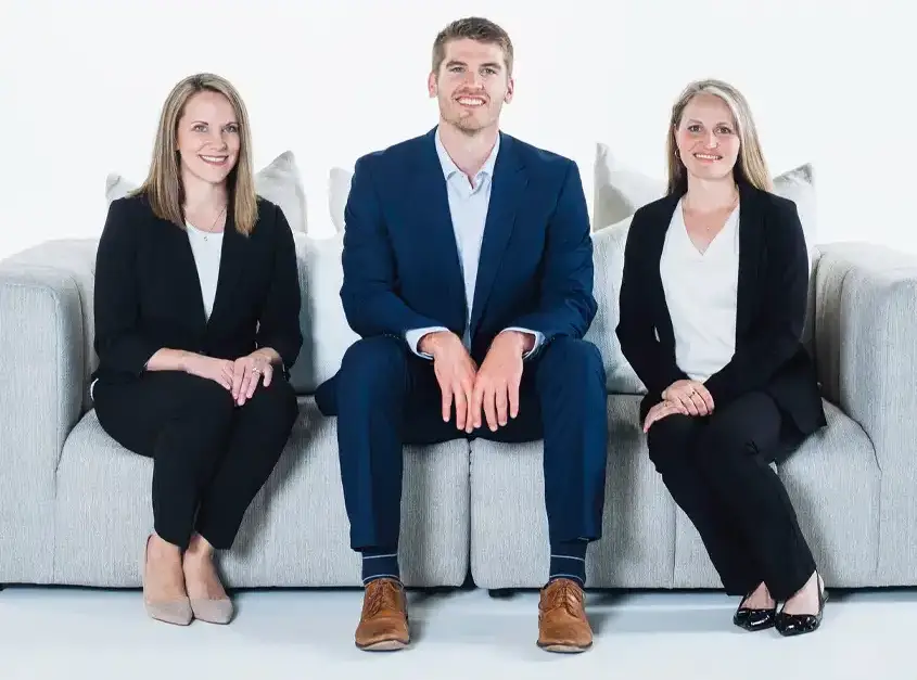 3 waterloo eye doctors sitting on a couch. pictured left to right, dr carrie menet, OD, dr brad boyle, OD, and dr carrie kearns, od.